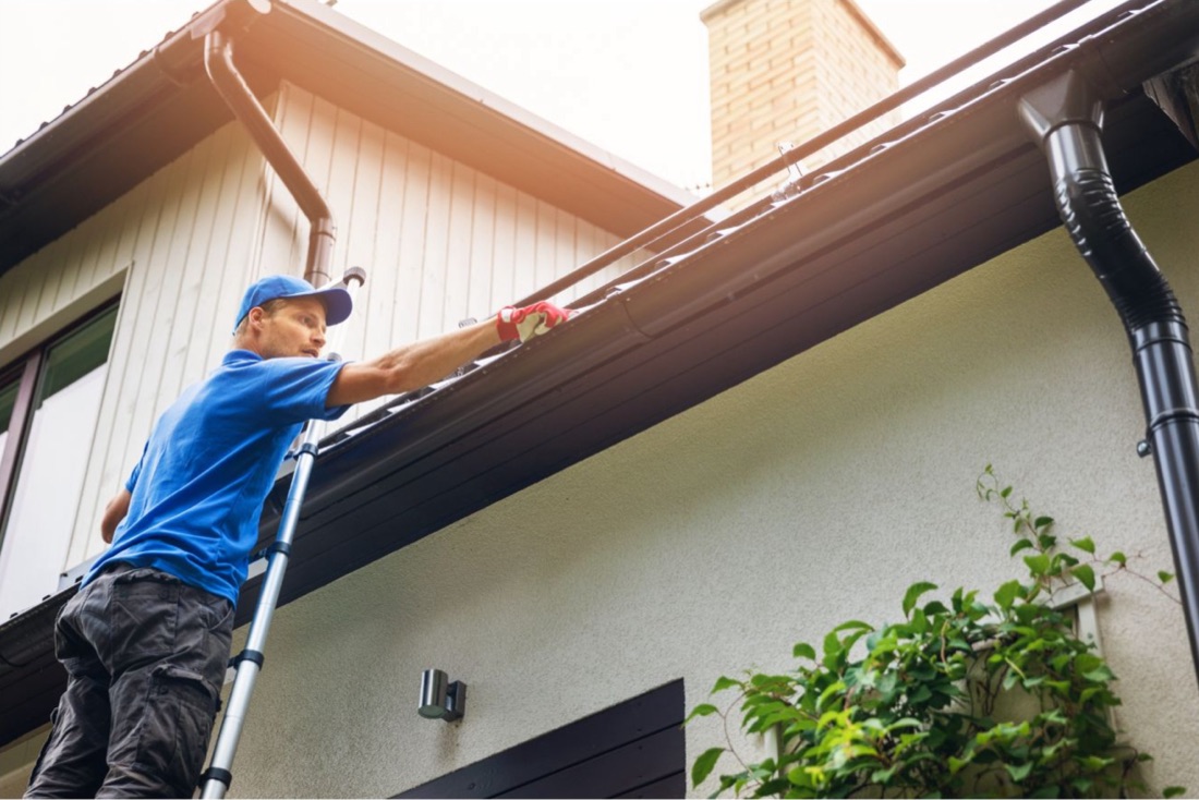 Technician installing seamless gutters on a Jacksonville home