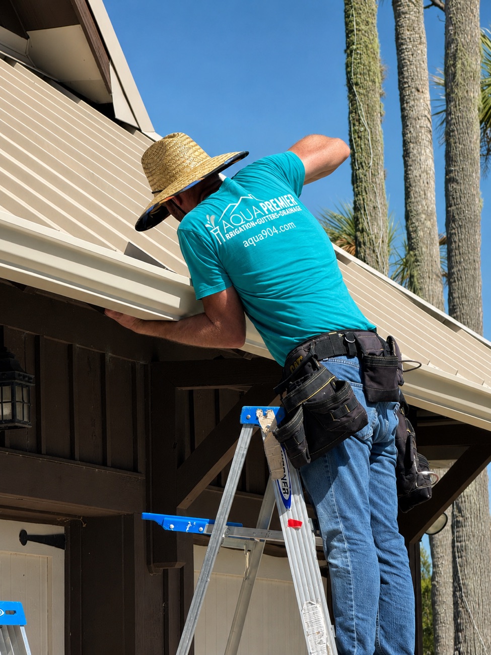 Aqua Premier installer fitting a new seamless aluminum gutter from a ladder — seamless rain gutter installation in Ponte Vedra Beach, Nocatee and Jacksonville (aqua904.com)